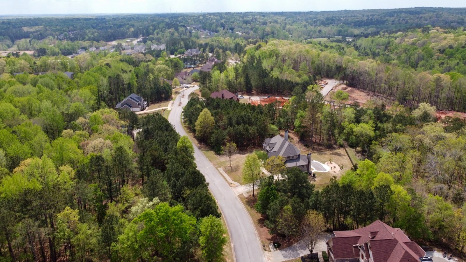 Aerial of a wooded parcel and community road — raw land under review