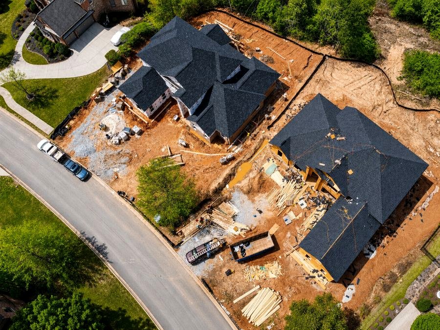 Aerial view of single-family homes under construction on adjacent lots